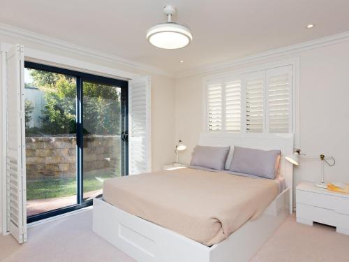 a white bedroom with a bed and a large window at Coastal Haven at Gerroa in Gerroa