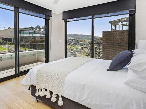 a bedroom with a large bed and large windows at Manhattan at SoHo in Gerringong