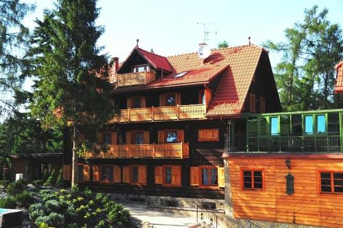 a large wooden house with a gambrel roof at Hotel Modrzewiówka in Lanckorona
