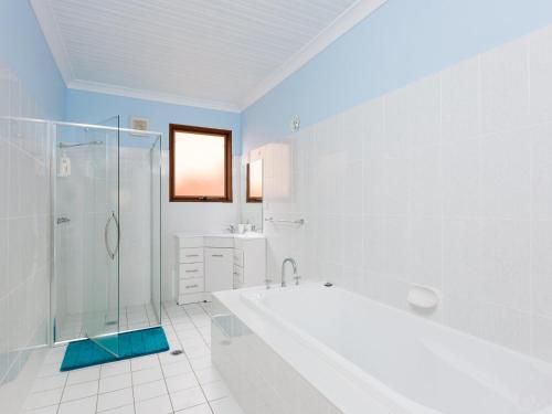 een witte badkamer met een bad en een douche bij Werri Views in Gerringong