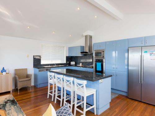 a kitchen with blue cabinets and a island with bar stools at Blue Waters at Gerroa in Gerroa