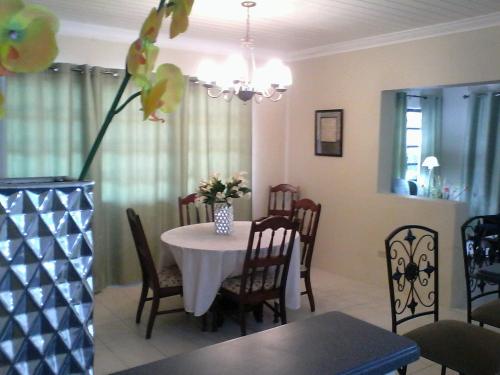 einen Esstisch mit einer Blumenvase darauf in der Unterkunft Gillys Dream in Nassau