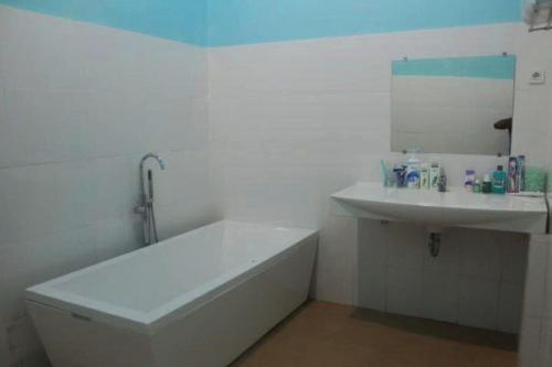 Baño blanco con bañera y lavamanos en GLOBAL VIEW HOTEL en Ende