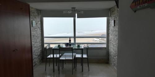 comedor con mesa, sillas y ventana en el Departamento Villa Gesell Sur Sobre Playa y 140 Vista al Mar en Villa Gesell