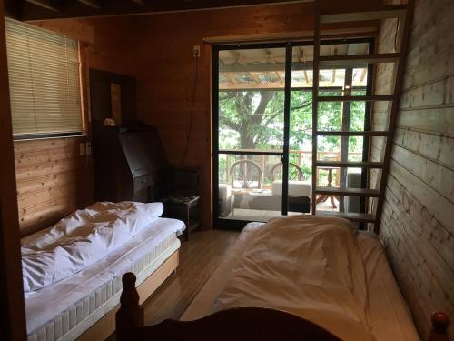 a room with two beds and a large window at Homey Inn Enya in Yufu
