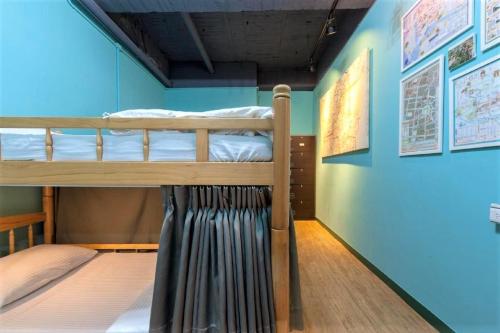 two bunk beds in a room with a blue wall at DongNing Atlas Hotel in Tainan