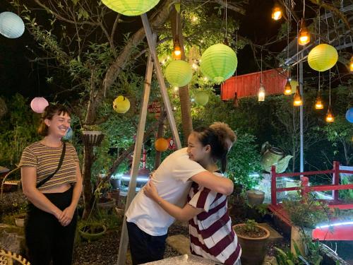 zwei Frauen stehen in einem Garten mit Papierlaternen in der Unterkunft Maison Teahouse homestay in Ha Giang