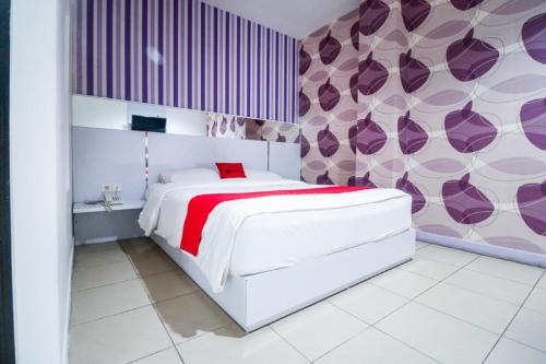 sypialnia z białym łóżkiem i fioletowymi ścianami w obiekcie RedDoorz near Terminal Batu Ampar w mieście Balikpapan