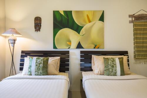 two beds in a room with a painting on the wall at Baan Lily in Chaweng