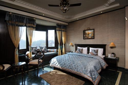 a bedroom with a bed and a couch and windows at Hotel Diplomat Residency in New Delhi