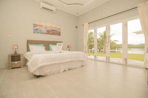 a white bedroom with a large bed and sliding glass doors at The Hawk's Nest Resort in Sabong