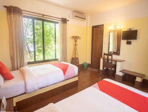a bedroom with two beds and a window and a television at Chitwan Riverside Resort in Sauraha