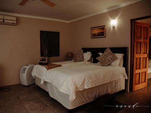 a bedroom with a large white bed and a fan at Foreva Wild in Klipdrift