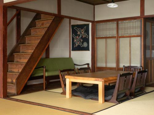 a dining room with a table and a staircase at Kyoto Machiya Cottage Karigane in Kyoto