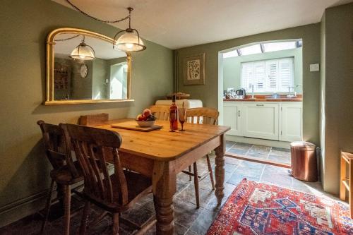 - une salle à manger avec une table en bois et un miroir dans l'établissement Bloom Cottage, à Aldeburgh