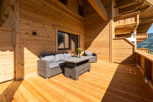 a porch of a log cabin with a couch and a table at Hotel Garni Romantik in Fügen