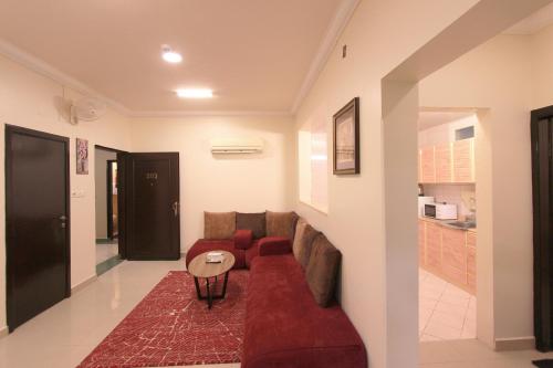 a living room with a red couch and a table at شقق منازل القصواء للشقق المخدومة إقتصادي in Buraydah