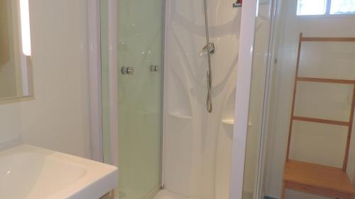 uma casa de banho branca com um chuveiro e um lavatório. em FRONT DE MER ET FALAISE 317 1er Étage Lit fait WifI em Le Tréport