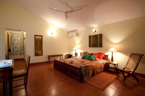 a bedroom with a bed and two chairs and a ceiling fan at Gitanjali Homestay in Mysore