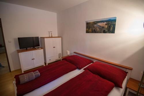 a bedroom with a bed with red sheets and a tv at Penzion Kryštof in Kovářská