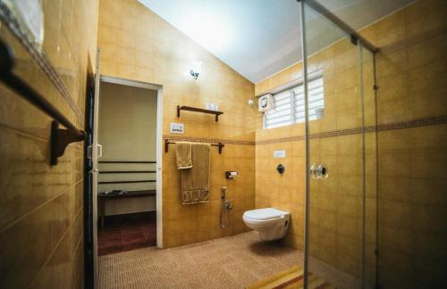 a bathroom with a toilet and a glass shower stall at Gitanjali Homestay in Mysore