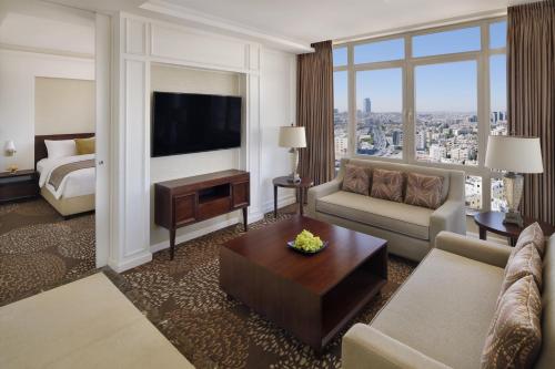 a living room with a couch and a bed and a television at Mövenpick Hotel Amman in Amman