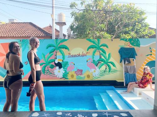 zwei Frauen stehen neben einem Schwimmbad in der Unterkunft Beach Hut Hostel in Kuta