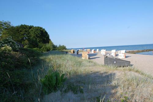 uma praia arenosa com cadeiras e o oceano em Schlafstrandkorb Nr. 1 em Sierksdorf