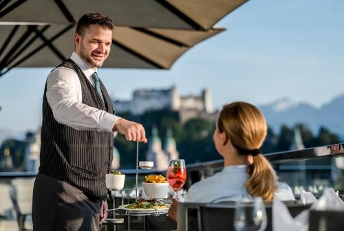 a man serving a plate of food to a woman at IMLAUER HOTEL PITTER Salzburg in Salzburg
