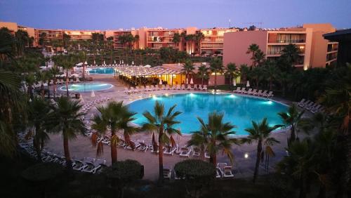 a view of a resort pool with palm trees and chairs at Apartamento T1 Herdade dos Salgados in Albufeira