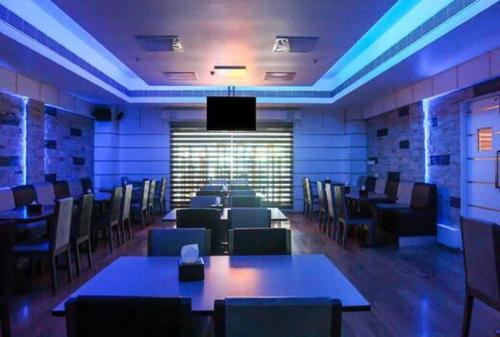 a dining room with tables and chairs and a television at Hotel Olive Eva in Kakkanad