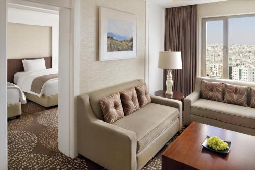 a hotel room with a couch and a bed at Mövenpick Hotel Amman in Amman