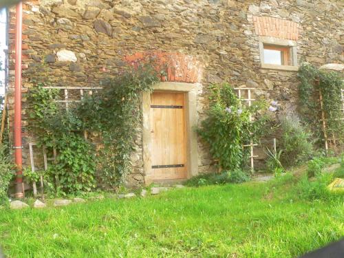 a stone house with a wooden door in the grass at STARA PLEBANIA in Lądek-Zdrój