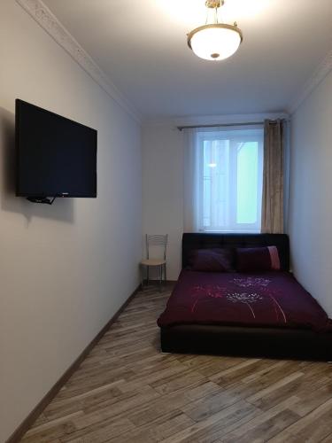 a bedroom with a bed and a flat screen tv at Apartment in Serbska Lviv in Lviv