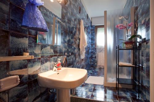 La salle de bains est pourvue d'un lavabo et d'un mur carrelé bleu. dans l'établissement B&B Residenza Bianco, à Castellana Grotte