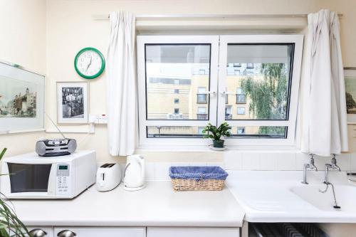 Biała kuchnia z kuchenką mikrofalową i oknem w obiekcie chez Guinevere w Londynie