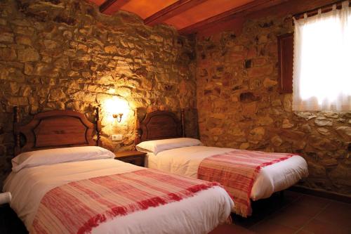 El Mangranar في Adzaneta: سريرين في غرفة بجدار حجري