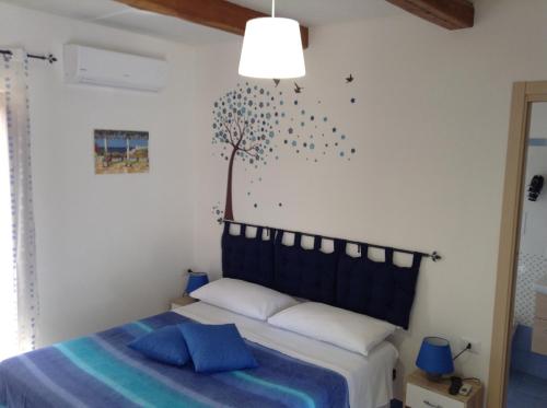 1 dormitorio con 1 cama y un árbol en la pared en Il Canto Dei Venti, en Montecorice