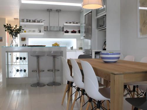 a kitchen with a wooden table and white chairs at Village Square 10 in Plettenberg Bay