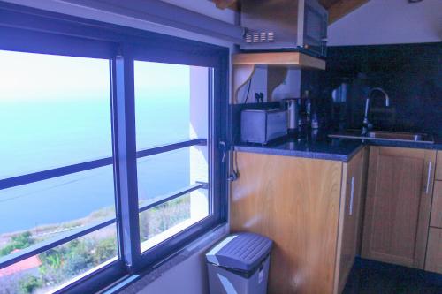 a kitchen with two windows and a counter with a sink at Studio One | Massapez | Fajã da Ovelha | Calheta in Fajã da Ovelha