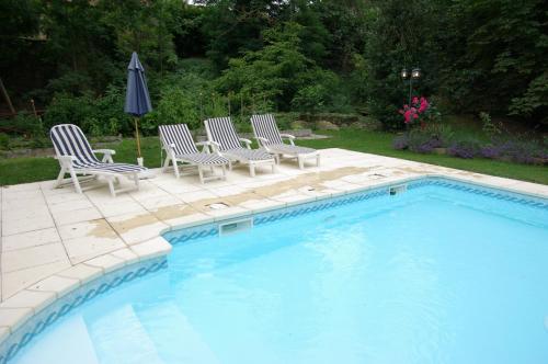 una piscina con sillas y una sombrilla junto a ella en L'Impasse du Temple, en Léran