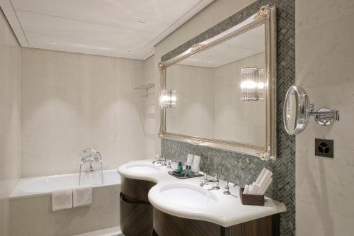 a bathroom with a sink and a mirror and a tub at Hotel Villa Honegg in Ennetbürgen