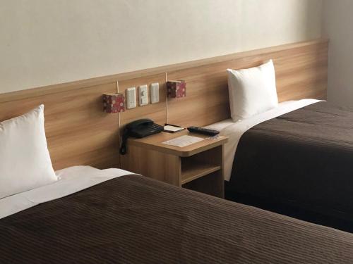 a hotel room with two beds and a desk with a phone at Izumisano Center Hotel Kansai International Airport in Izumi-Sano