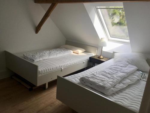 two beds in a attic bedroom with a window at Deichhof von 1843 in Tossens direkt an der Nordsee für 12 Personen in Butjadingen