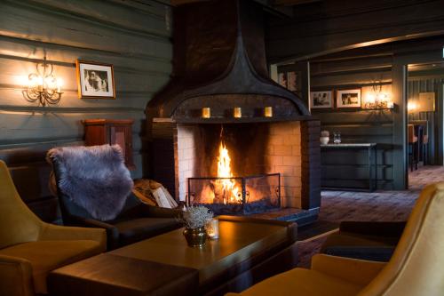 a fireplace in a living room with couches and a table at Geilo Hotel in Geilo