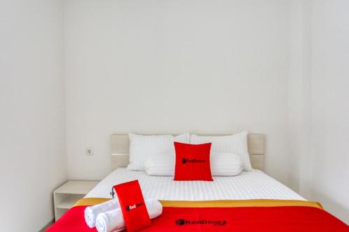 Schlafzimmer mit einem Bett mit roten und weißen Kissen in der Unterkunft RedDoorz @ Plemburan Jakal 2 in Yogyakarta