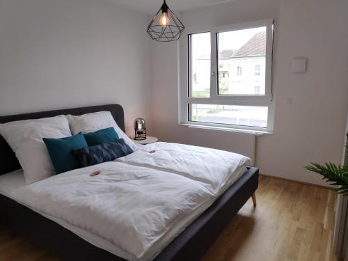 a bedroom with a bed with white sheets and a window at City Appartement Wien-Schwechat in Schwechat