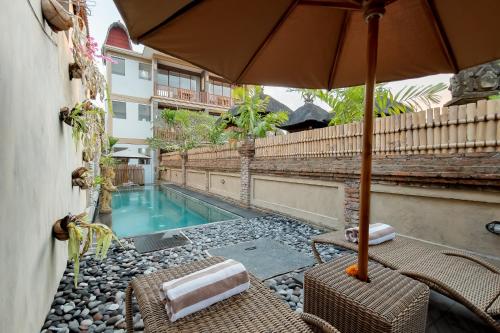 a patio with chairs and an umbrella and a swimming pool at Santosha Place in Ubud