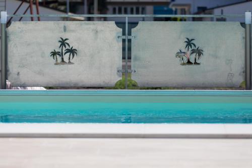 a view of a swimming pool with palm trees on a wall at Veda elegant rooms in Fiumefreddo di Sicilia