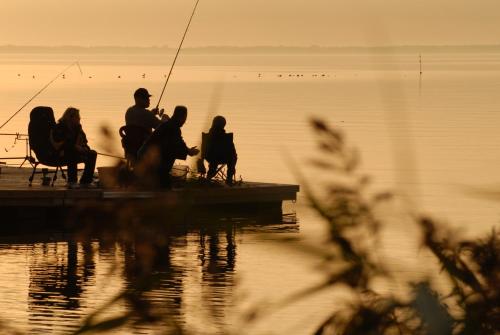 a group of people fishing on a dock on the water at Vila Baldininkas in Neringa